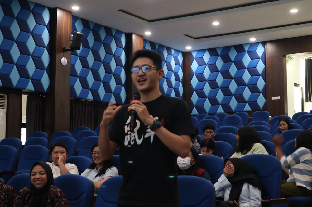 Seorang mahasiswa berbicara dengan mikrofon saat sesi tanya jawab kuliah tamu